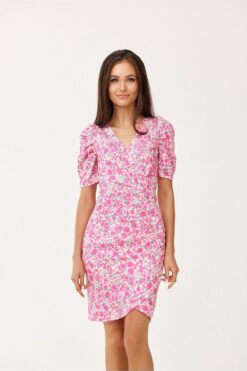 Femme brune portant la robe Gaïa à imprimé floral rose avec encolure cache-cœur et manches bouffantes